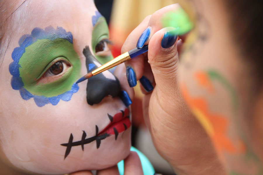 kid getting face painted for día de los muertos
