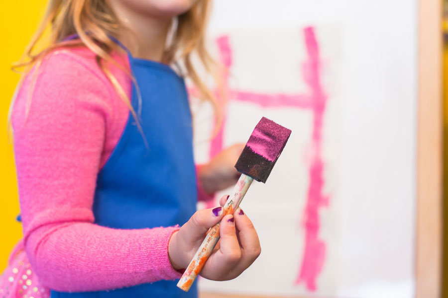 little girl holding a paint brush